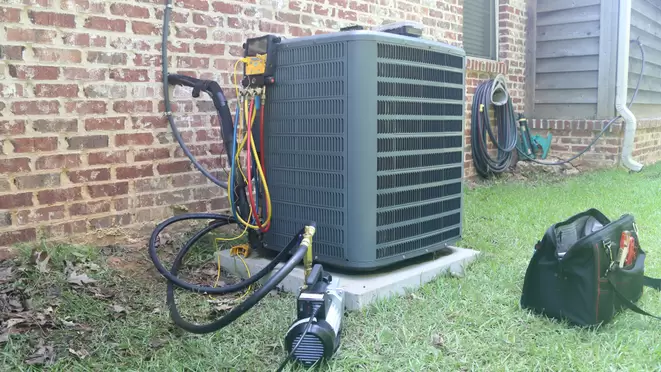 An outdoor AC unit with a technician's tools next to it