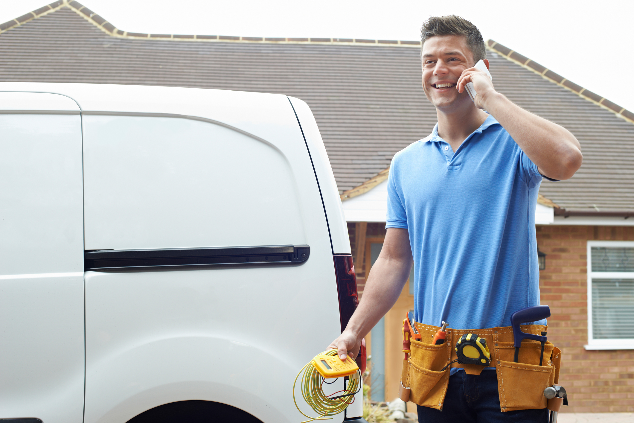 Technician in front of white work van on the phone