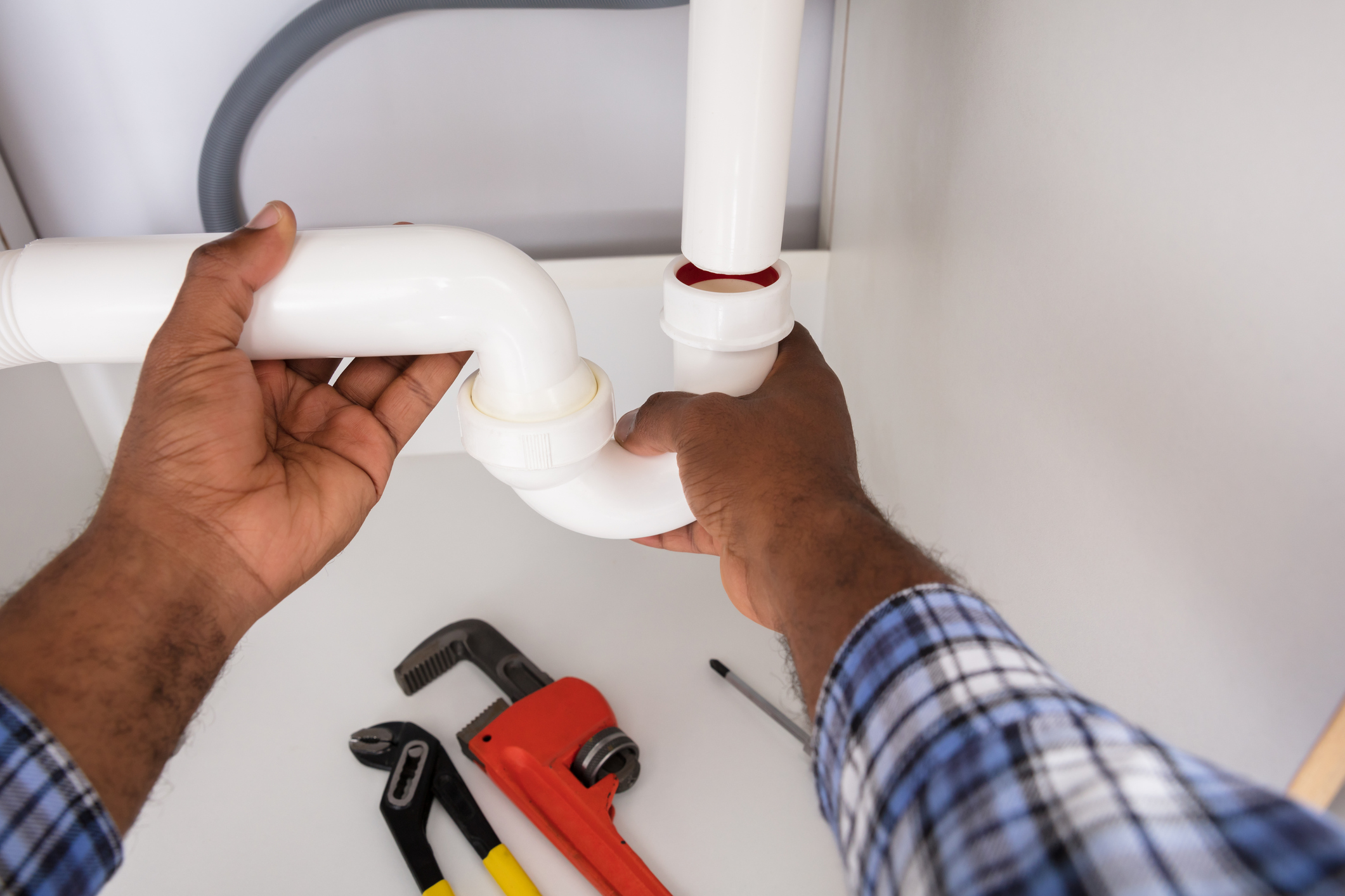 Plumber replacing piping under a sink