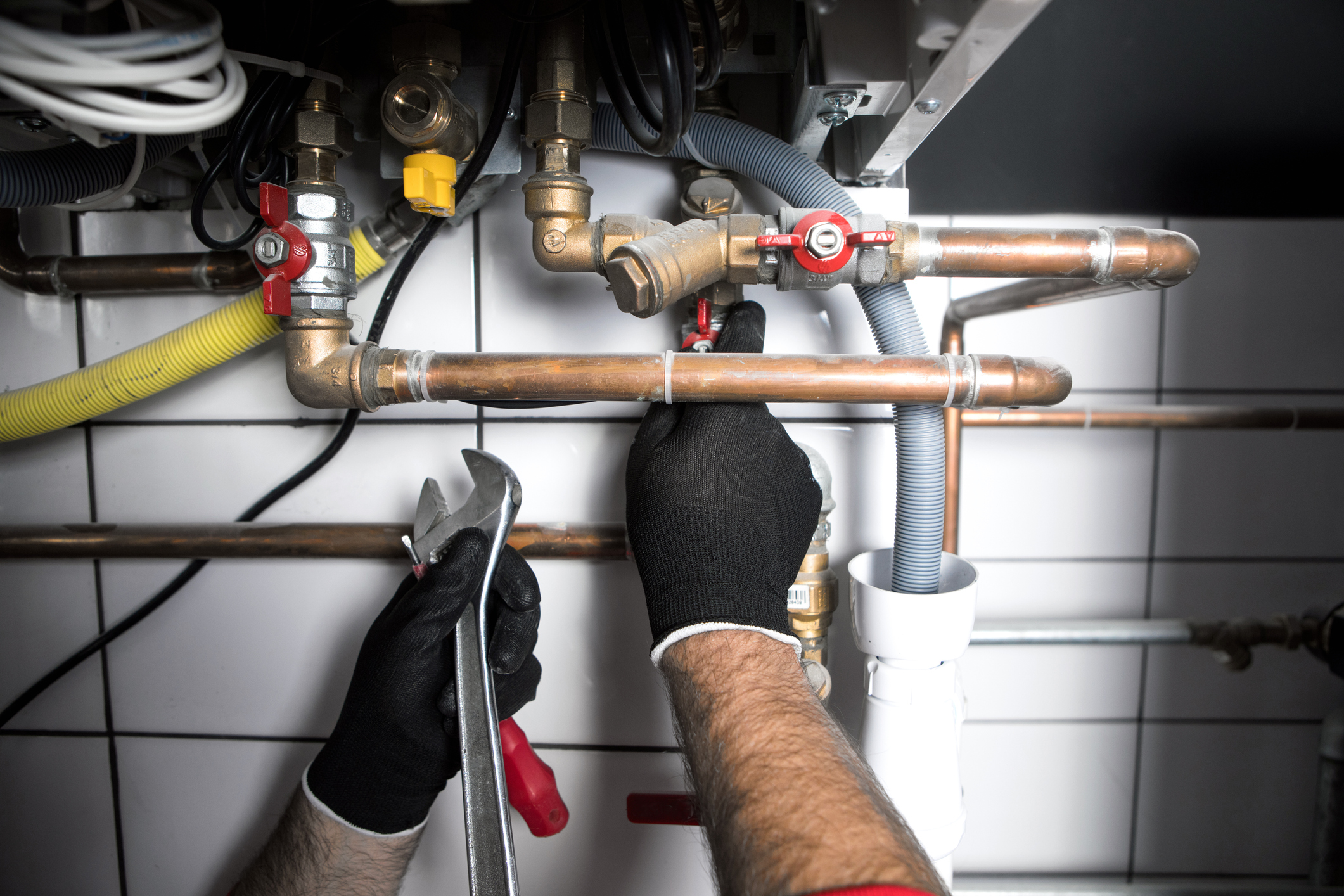 A plumber adding new plumbing pipes below a counter