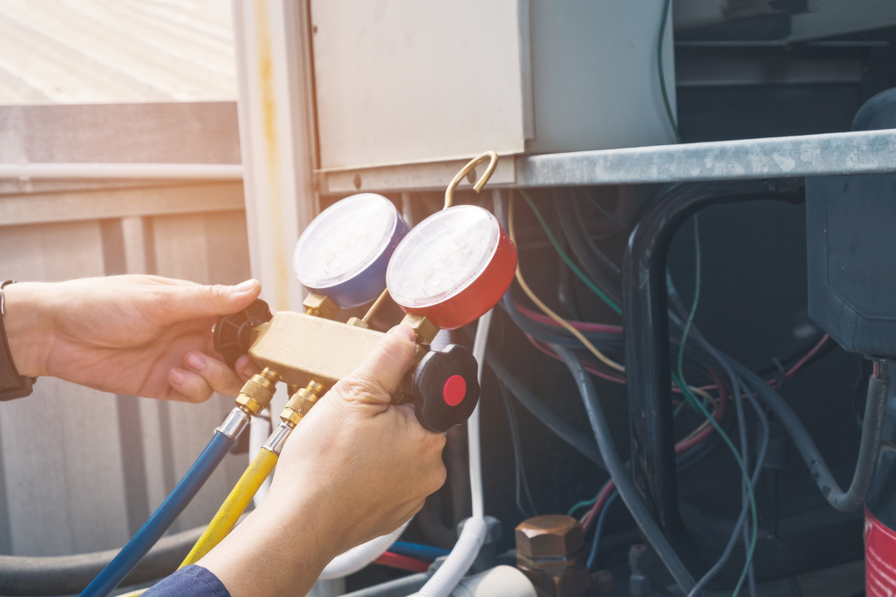 Hands on HVAC pressure gauge checking a commercial HVAC system