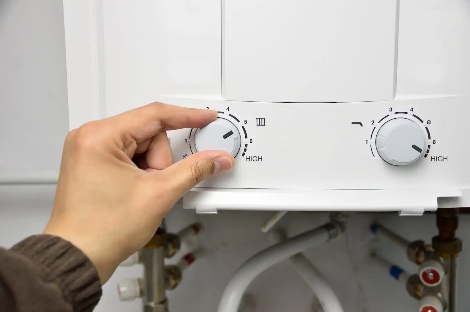 Homeowner’s hand on the temperature knob of a tankless water heater