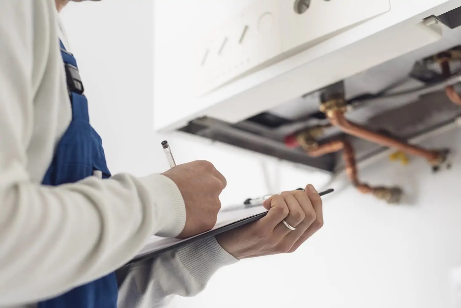 A technician with a clipboard standing in front of a boiler