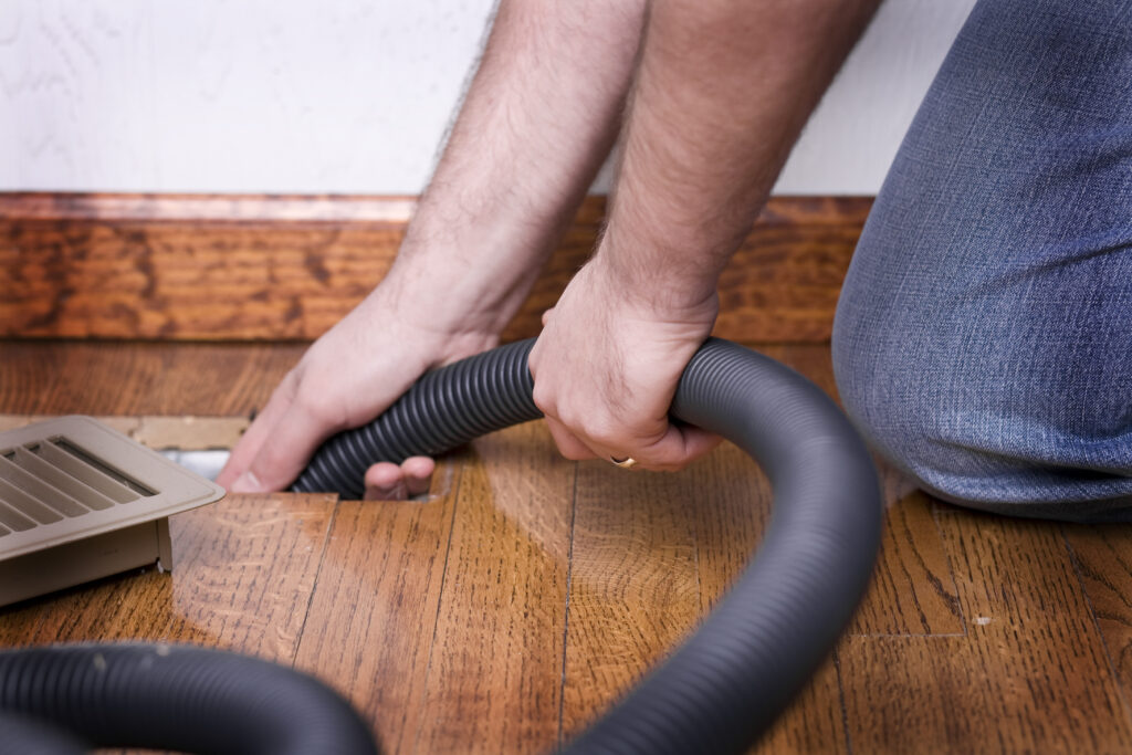 HVAC tech using high powered vacuum to clean air ducts